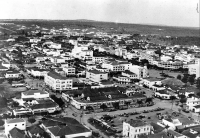 Fotografia do setor central de Goiânia na década de 1950, com o antigo prédio do mercado central em primeiro plano, o Morro da Serrinha na parte superior central da foto e a Serra das Areias na porção superior direita. A topografia plana foi fator decisivo na escolha pela mudança da capital de Goiás. Fotografia do arquivo do Jornal O Popular, publicada na reportagem "O fim do Isolamento: aqui, trem das cores, sábios projetos", de Rogério Borges em 20/10/2023.