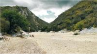 Visão geral do início do geossítio formado por serras de quartzitos por onde passa o rio Picuí. Na foto aparece o leito seco do rio (Nascimento & Ferreira, 2012).